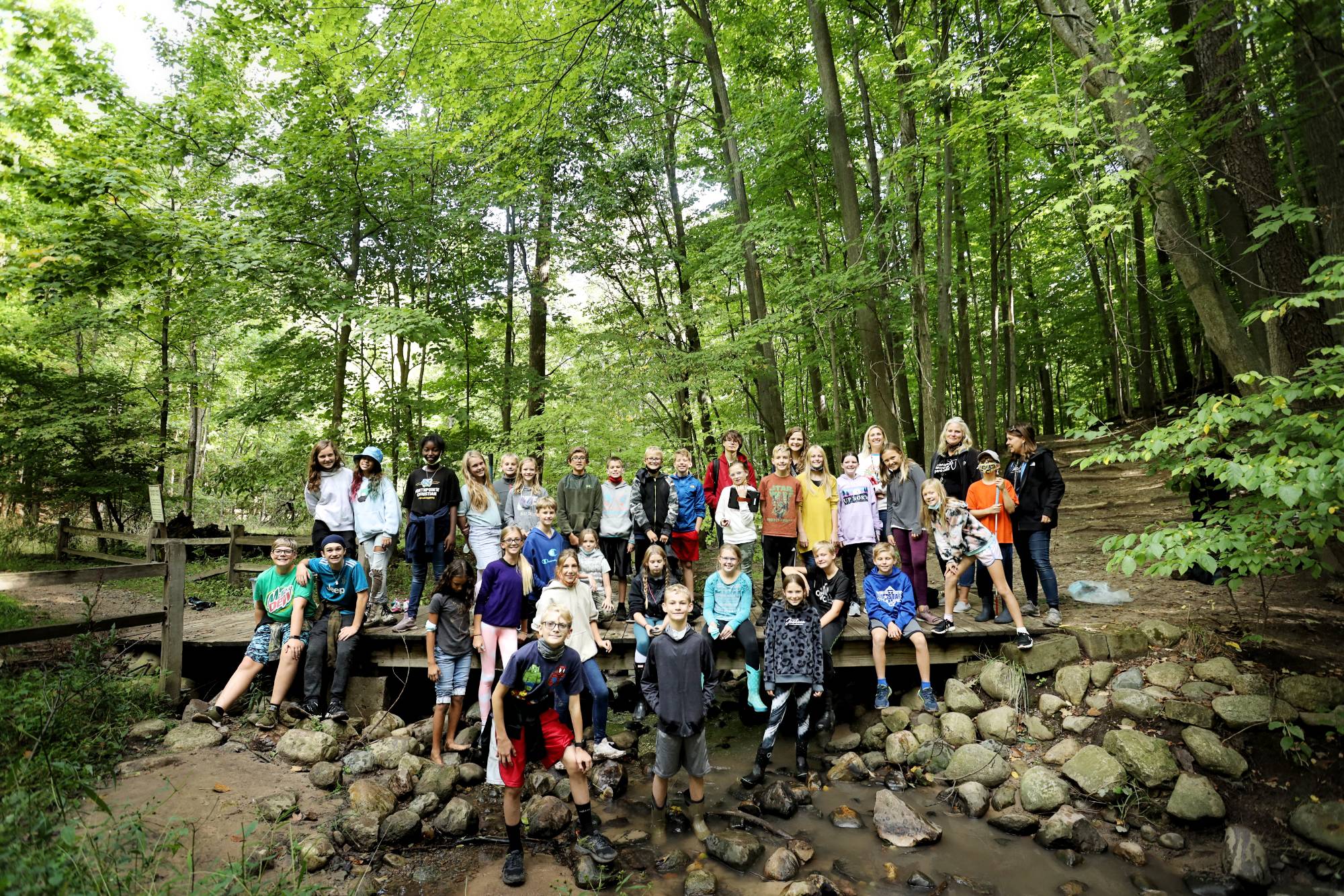 Group of Groundswell Stewardship Initiative students smiling after completing an action project in the woods